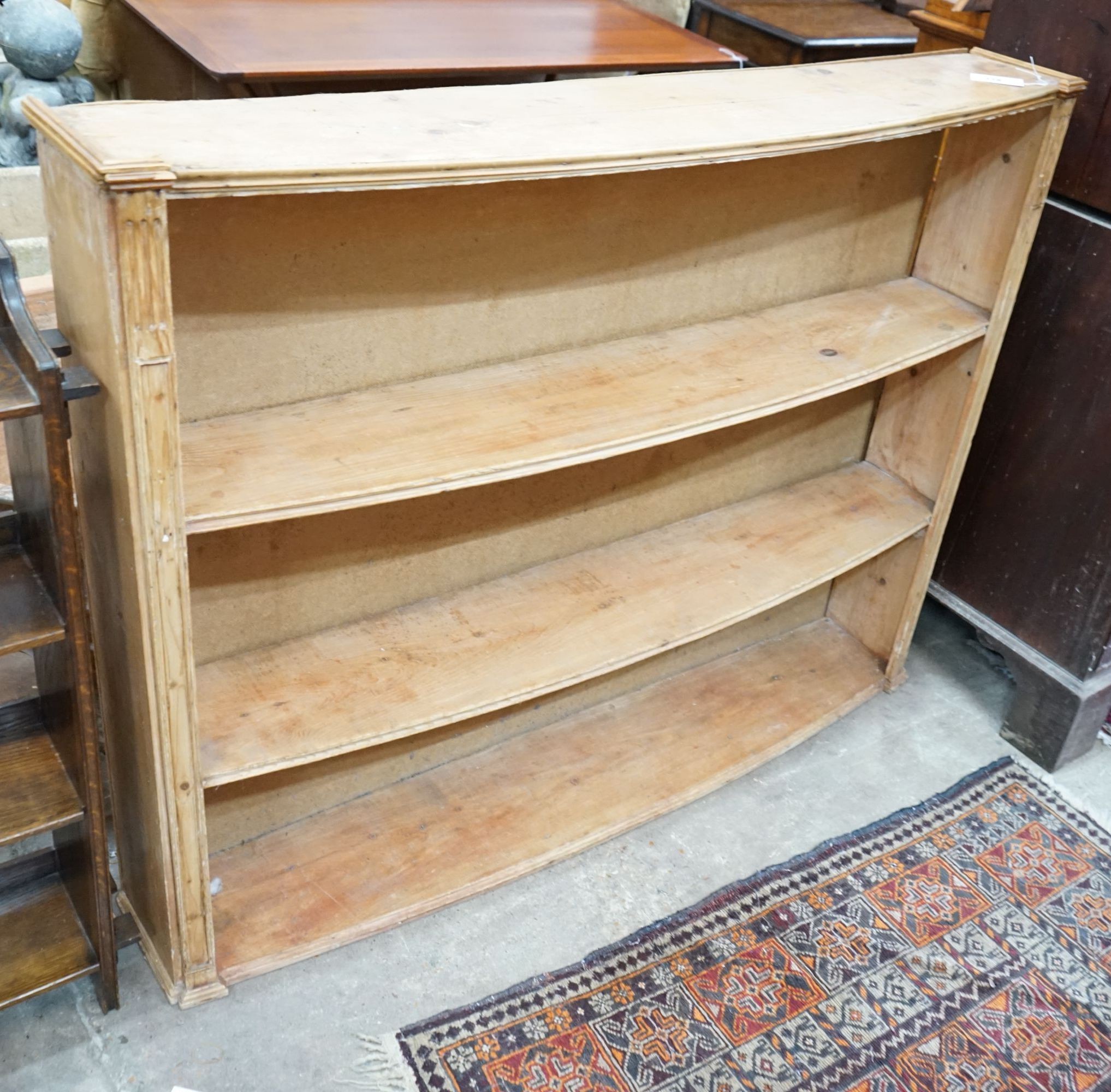 A 19th century pine bow front open bookcase, adapted, width 139cm, depth 24cm, height 107cm